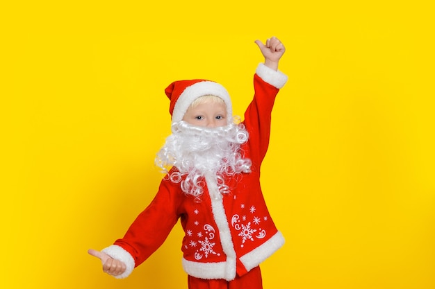 Threeyearold child in Santa Claus clothes and with a white beard shows a thumbs up gesture