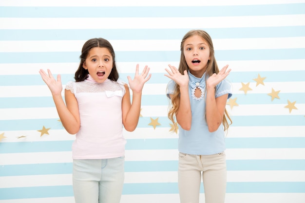 Thrilled moment from childhood. Kids schoolgirls preteens shocked. Girls surprised shocked faces thrilled expression stand striped background. Girls children best friends wonder about surprising news.