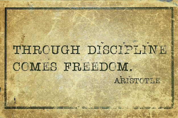 Through discipline comes freedom - ancient Greek philosopher Aristotle quote printed on grunge vintage cardboard