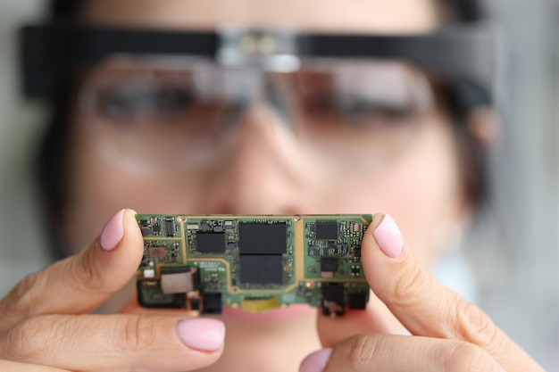 Through magnifying lens, engineer looks at computer chip