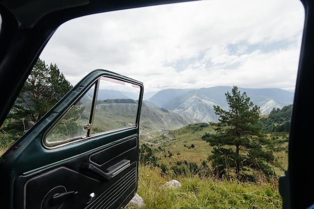 Through the open car door, you can enjoy a stunning view of the\
mountains and woodlands. travel and tourism.