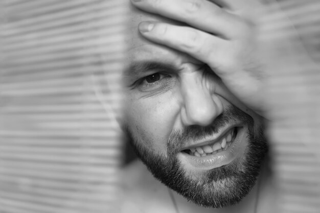 Photo through wooden blinds the man looks