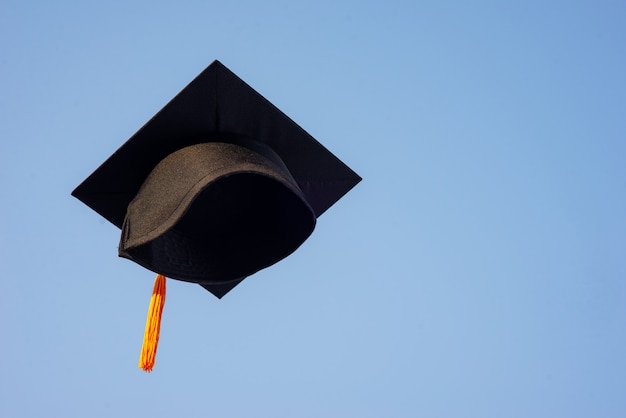 Photo throw a black hat of graduates in the sky.