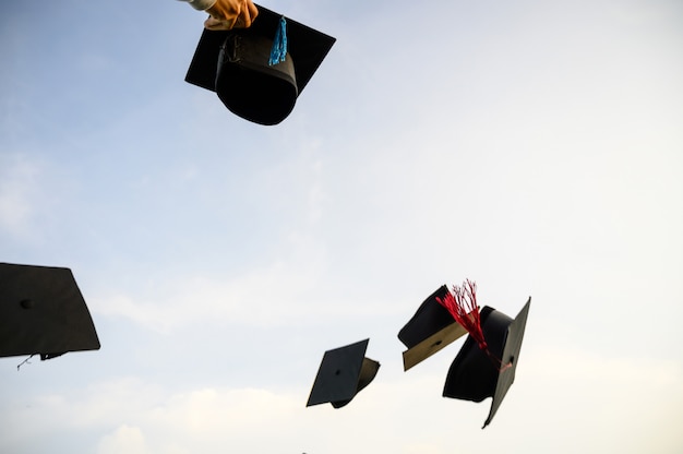 Photo throw a black hat of graduates in the sky.