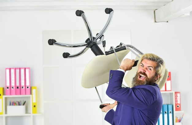 Throw out chair get out of my office drive out uninvited guest\
stress concept crazy or mad businessman standing in office hold\
chair business man aggressive hipster man angry with office\
chair