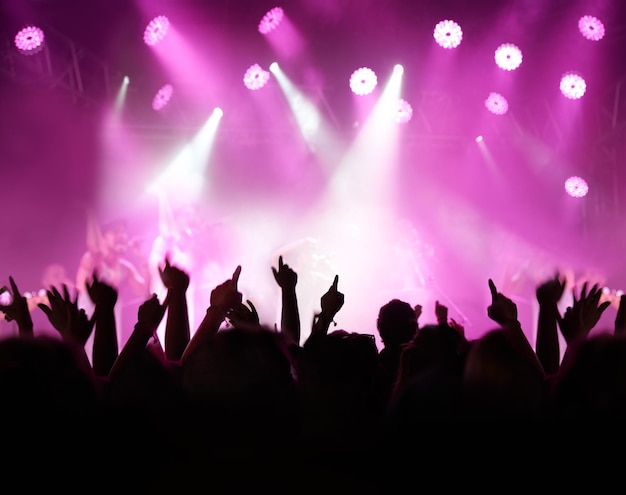 Throw your hands up. Rearview of an audience with hands raised at a music festival and lights streaming down from above the stage.