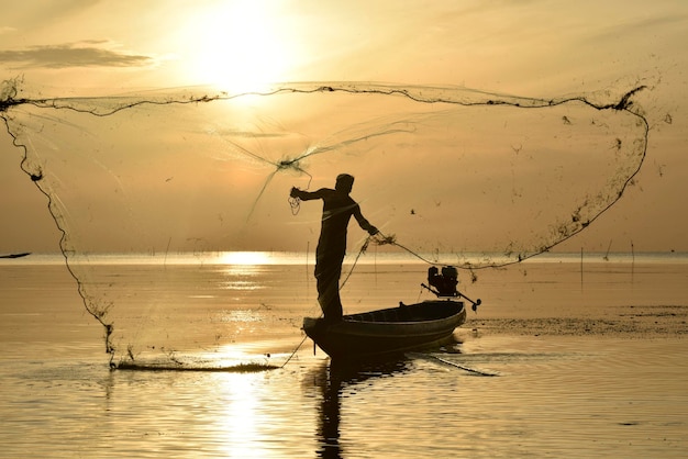 Throwing fishing net with gold sunrise in background