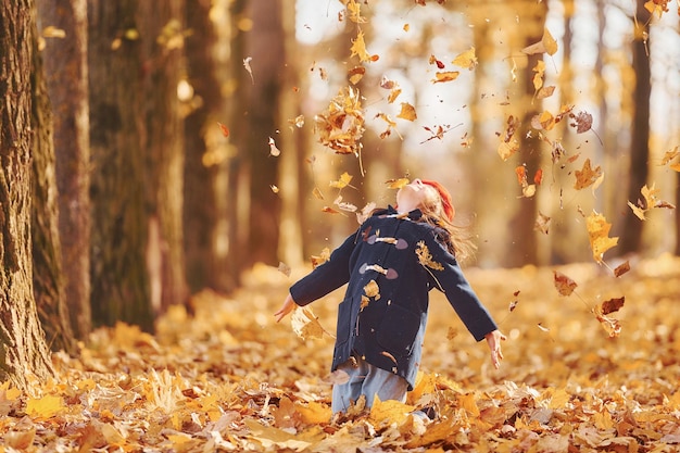 Throwing leaves into the air Cute positive little girl have fun in the autumn park