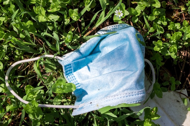 Thrown a medical mask on the grass. The concept of environmental pollution with garbage and household waste disposal.