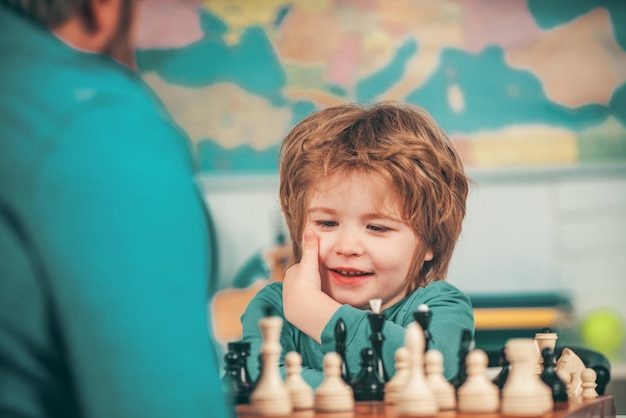 Thuis educatieve spelletjes kleuter of schooljongen vrolijk lachend jongetje zittend aan tafel