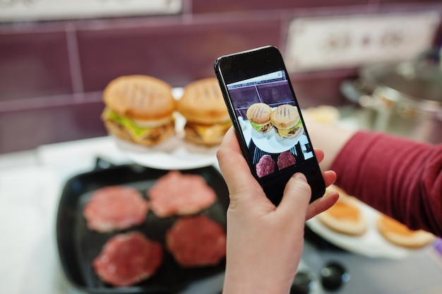 Thuis hamburgers bakken in de keuken tijdens quarantainetijd. Foto maken op mobiele telefoon.