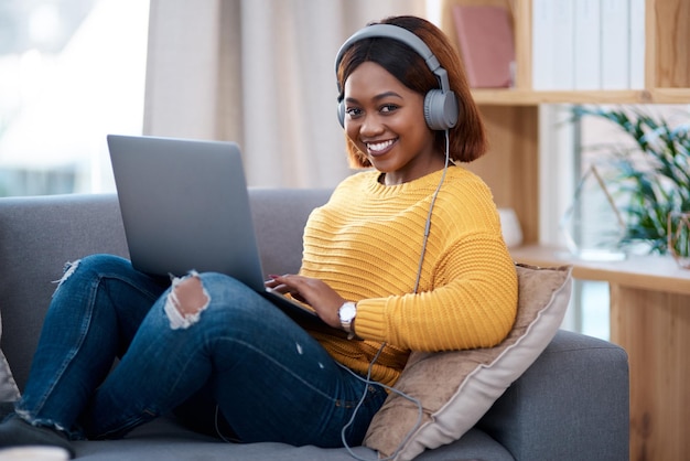 Thuis is mijn gelukkige plek Foto van een aantrekkelijke jonge vrouw die een koptelefoon draagt terwijl ze haar laptop gebruikt