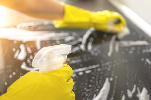 Thuis keukentafel schoonmaken met desinfecterend spuitfles wasoppervlak met handdoek en handschoenen