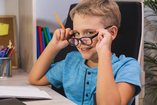 Thuis leren online onderwijs gelukkig schooljongen met bril studies thuis jongen kijkt naar de camera