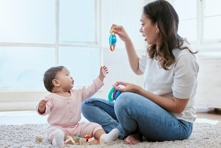 Foto thuis moeder en baby met speelgoed voor het spelen van binding en kindontwikkeling op de vloer in de kleuterschool ontspannen moeder en baby dochter op het tapijt samen met spelletjes voor groei motorische vaardigheden en leren
