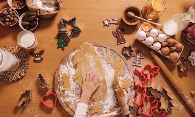 Thuis peperkoek maken klein meisje snijdt koekjes van peperkoekdeeg kerst en nieuwjaar