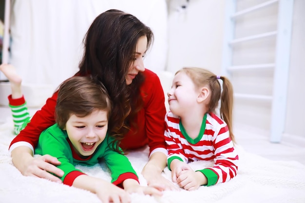 Thuis rust een gezin in gestreepte pyjama uit. Kleine kinderen verkleed als elfjes liggen op de bank. Een blije familie.