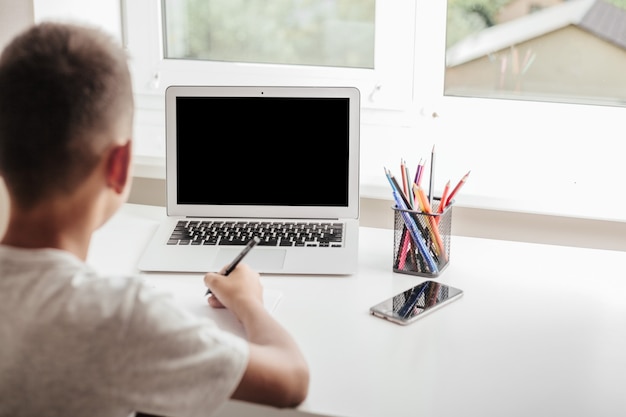 Foto thuis school door middel van online homeschooling. het kind zit achter de computer