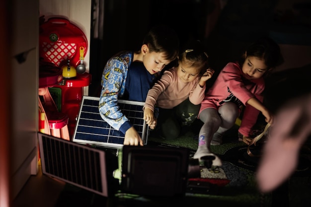 Thuis spelende kinderen tijdens een black-out met behulp van alternatieve verlichting met zonnepaneel