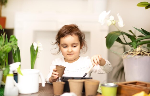 Thuis tuinieren klein meisje helpt bij het verzorgen van huisplanten groene omgeving thuis planten zaden