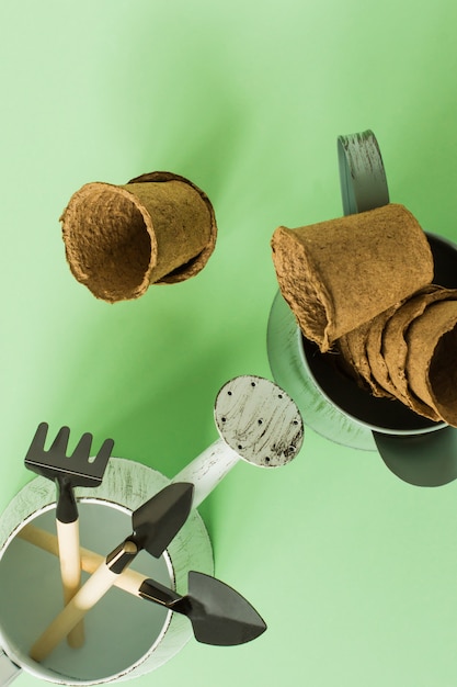 Thuis tuinieren. Voedsel verbouwen op de vensterbank. Gereedschap, turfpotten en geperste grond voor zaailingen. bovenaanzicht. Flatlay op groene achtergrond.