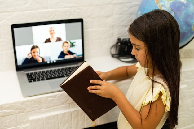 thuis, vrije tijd, technologie en internetconcept - klein studentenmeisje met laptop thuis, klein meisje maakt gebruik van videochat