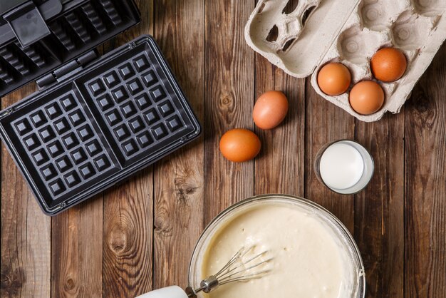 Thuis wafels maken - wafelijzer, beslag in kom en ingrediënten - melk en eieren.