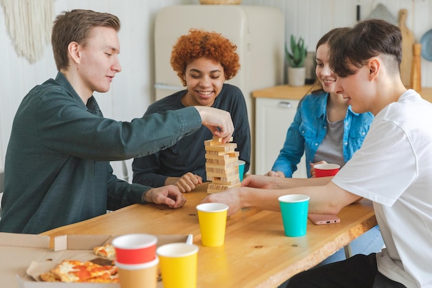 Thuisfeestvrienden die samen tijd doorbrengen met spelen in bordspel crash houten toren thuis gelukkig div