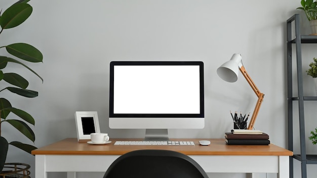 Thuiskantoor bureau met leeg scherm computermonitor en benodigdheden op houten tafel Leeg scherm voor montage van grafische weergave