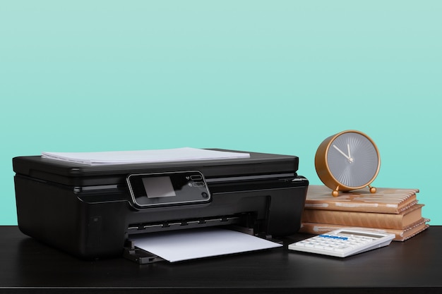 Thuislaserprinter op bureau tegen groene achtergrond