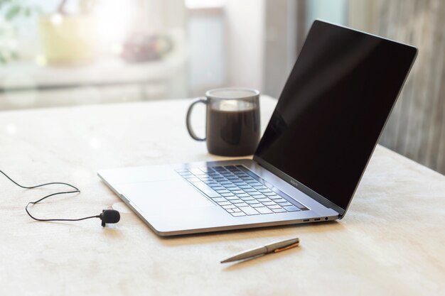 Thuisonderwijs of werk buiten kantoorconcept. Laptop met een microfoon en kopje koffie op de tafel