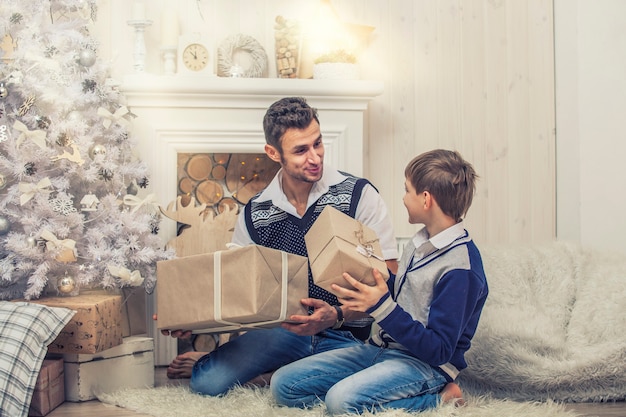 Thuisvader met kind op zoek naar dozen met cadeaus in het kerstinterieur