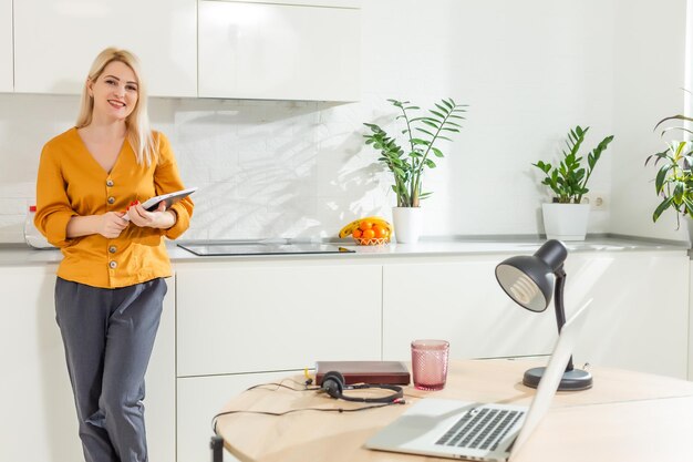 Thuiswerken op afstand. Jonge vrouw die laptop met behulp van. Freelancer werkplek in keuken kantoor. Telewerken in isolatie, vrouwelijk bedrijf, online winkelen. Student in afstandsonderwijs. Lifestyle-momentje.