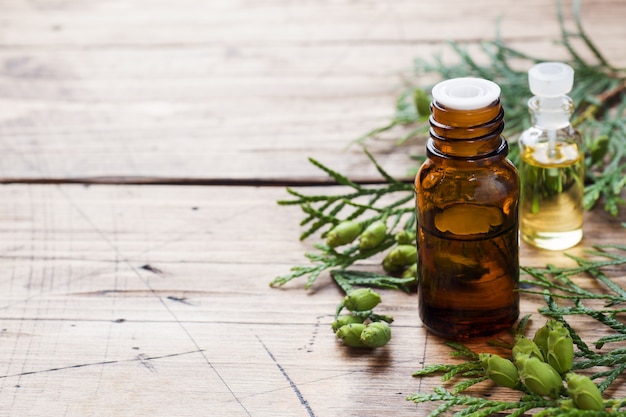 Thuja aroma essential oil in a glass jar on wooden surface