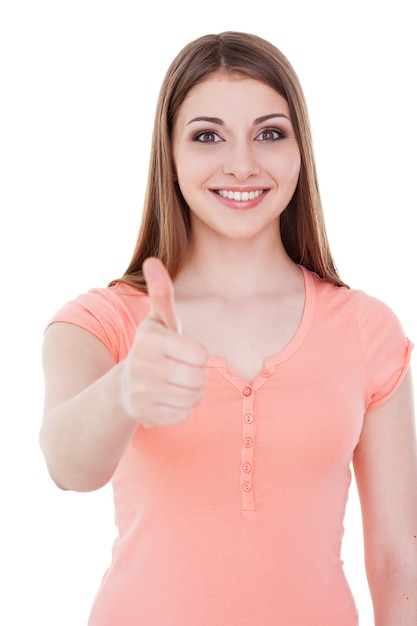 Thumb up. beautiful young smiling woman looking at camera and holding her thumb up while standing isolated on white