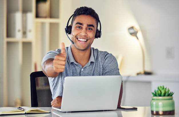 Thumbs up by call center looking pleased and showing support with hand gesture while working on a laptop in an office alone at work Portrait of an excited customer service agent expressing thanks