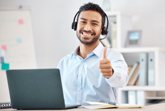 Photo thumbs up call center and customer service with a man saying thank you and working in sales or telemarketing crm contact us and consulting with a male consultant giving a yes gesture in an office