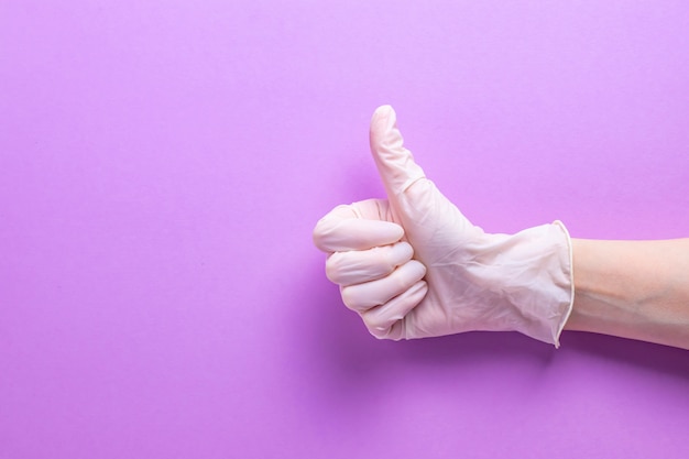 Thumbs up on a hand with rubber gloves on purple background
