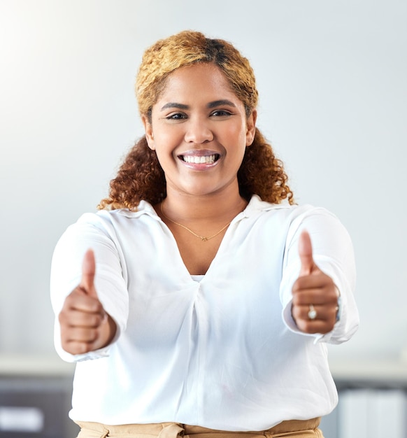 Thumbs up thank you and motivation with a business woman and winner in her office with a smile Hands happy and success with a winning female employee saying yes and standing in her workplace