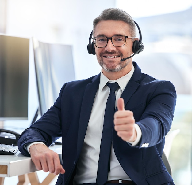 Thumbs up yes and success deal for a call center agent with contact us and happy about telemarketing Portrait of a CRM manager or customer service employee smiling due to good business