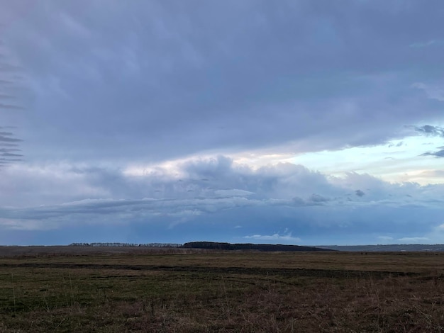 雷雲と丘のある春の野原