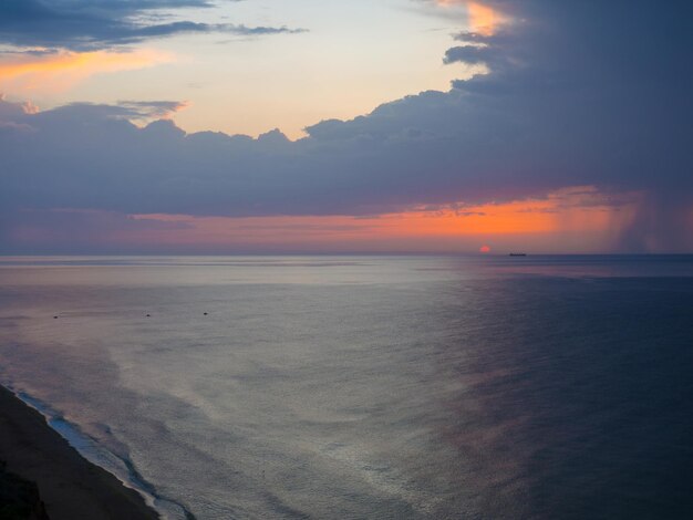 夕暮れ時の海での雷雨日の出の美しさは波打つアラブ首長国連邦の劇的な曇り空と昇る太陽の海の景色ビーチからの眺め