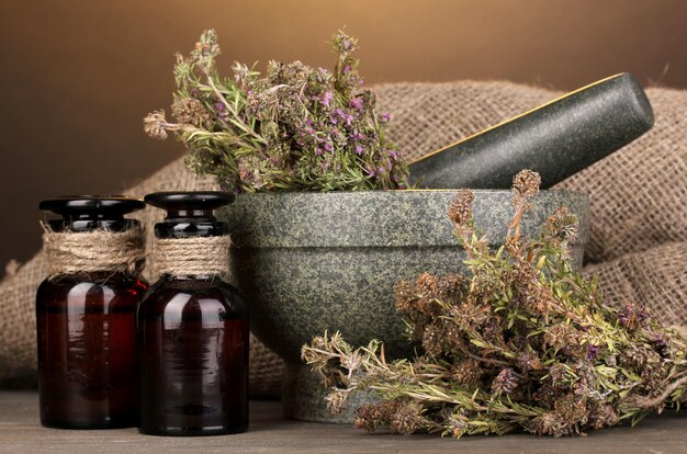 Thyme herb and mortar on wooden table on brown background