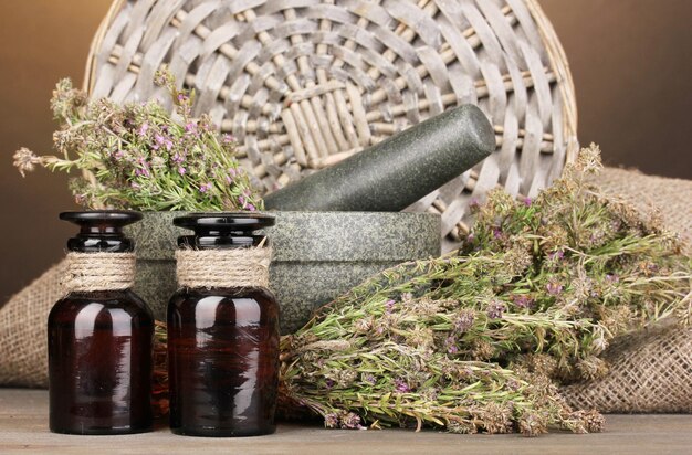 Photo thyme herb and mortar on wooden table on brown background