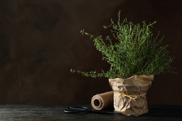 Thyme on wooden table against brown background