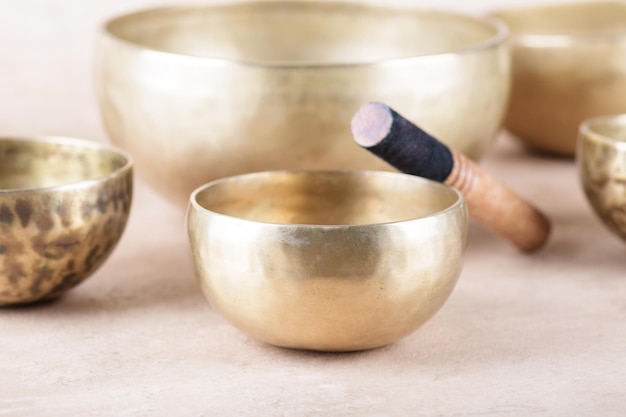 Photo tibetan singing bowls with sticks used during mantra meditations on beige stone background close up