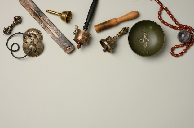 Photo tibetan singing copper bowl with a wooden clapper on a gray background, objects for meditation and alternative medicine, top view, copy space