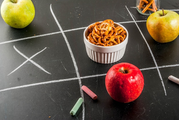 Tic tac toe healthy and unhealthy snack concept with crackers, chips and apples