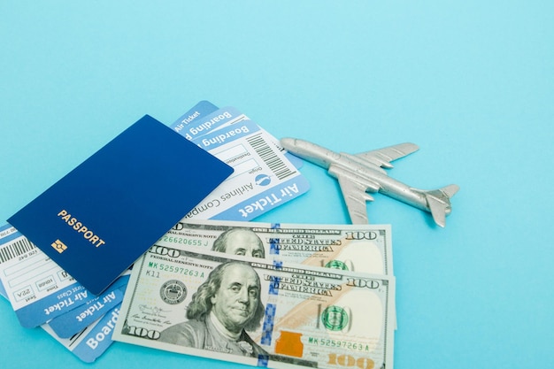 Biglietti per dollari aerei e passaporti con modello di aereo su sfondo blu copia spazio per il testo