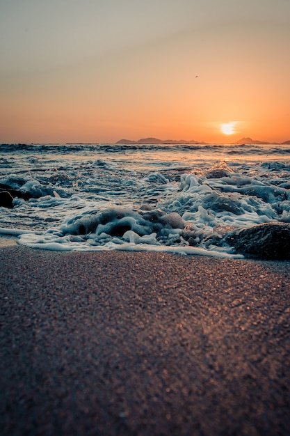 Tides breaking in the sand of the beach during a sunset